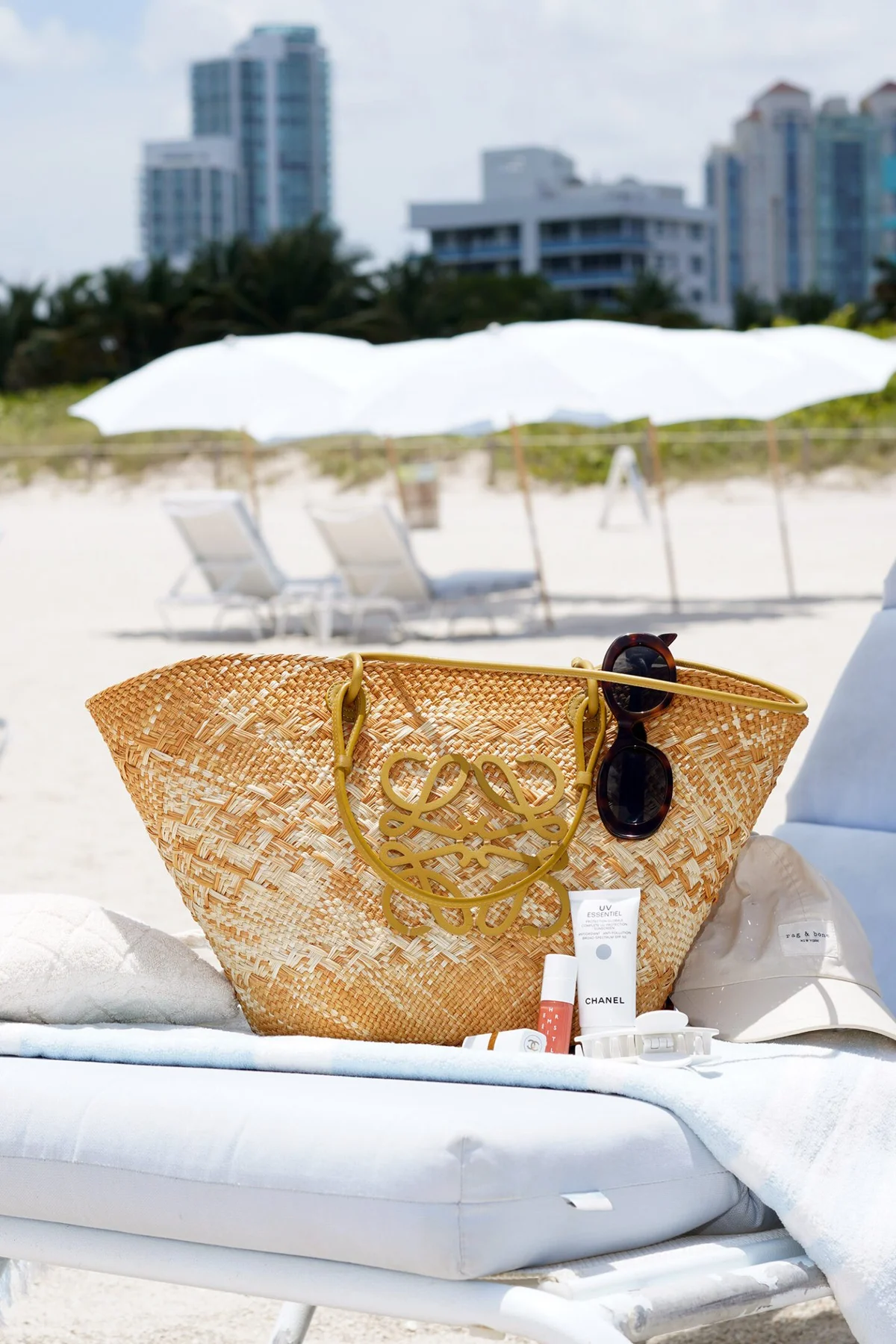 Straw bag, sunscreen and hat laid out on a beach lounge chair