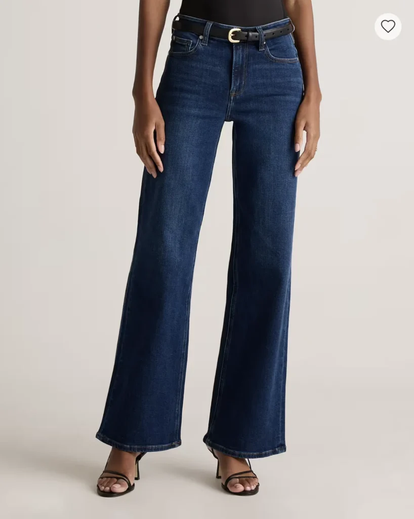 Model in dark wide-leg high-waist jeans with black belt and heels