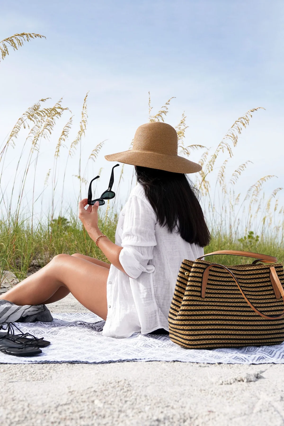 Beach towel scene with wide-brim hat, tote and flip-flops