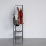 Minimalist fashion designer's studio with clean-lined garments on racks, soft natural light