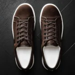 Brown suede low-top sneaker with white sole on neutral background
