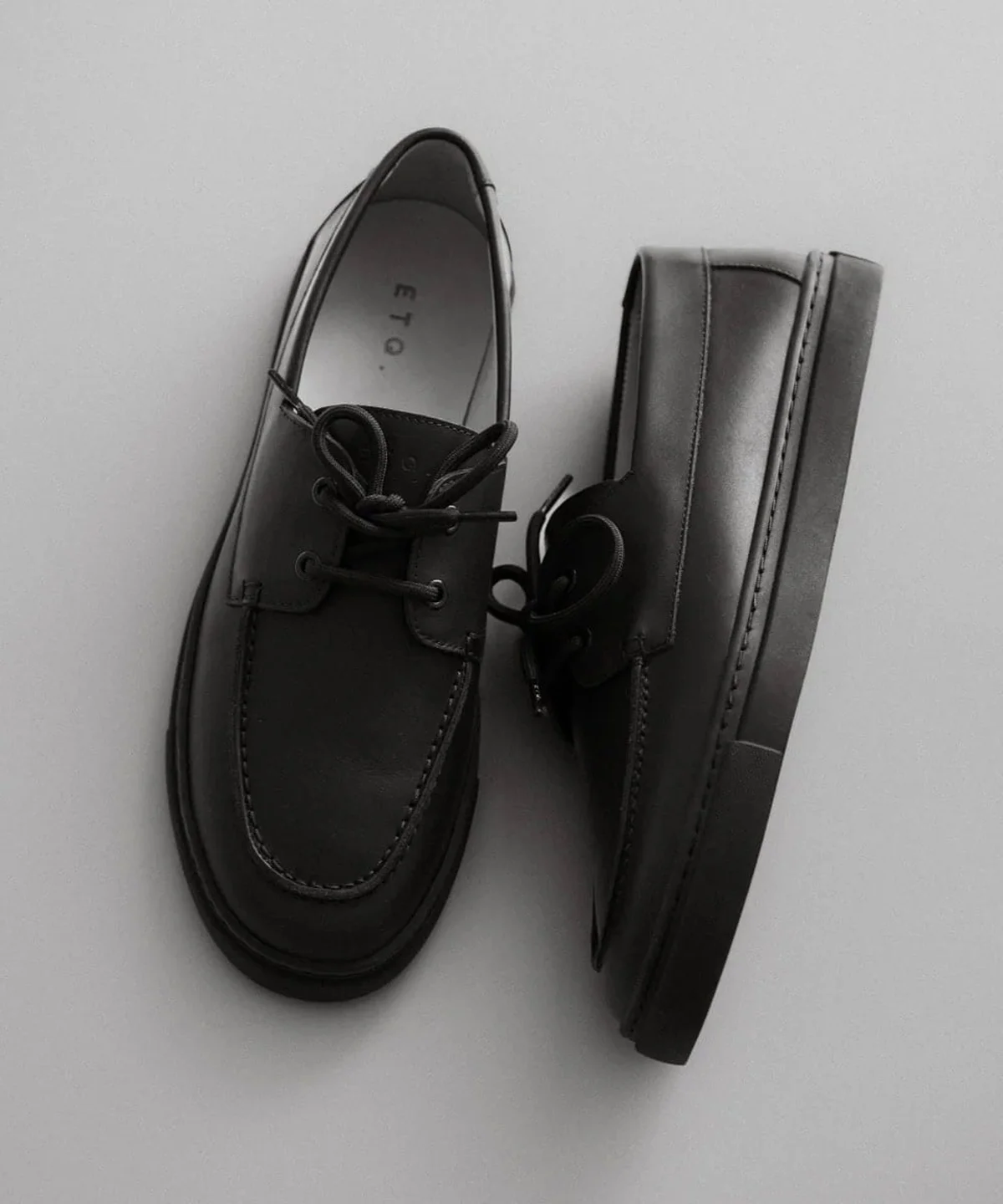 Black leather lace-up shoe on light gray background